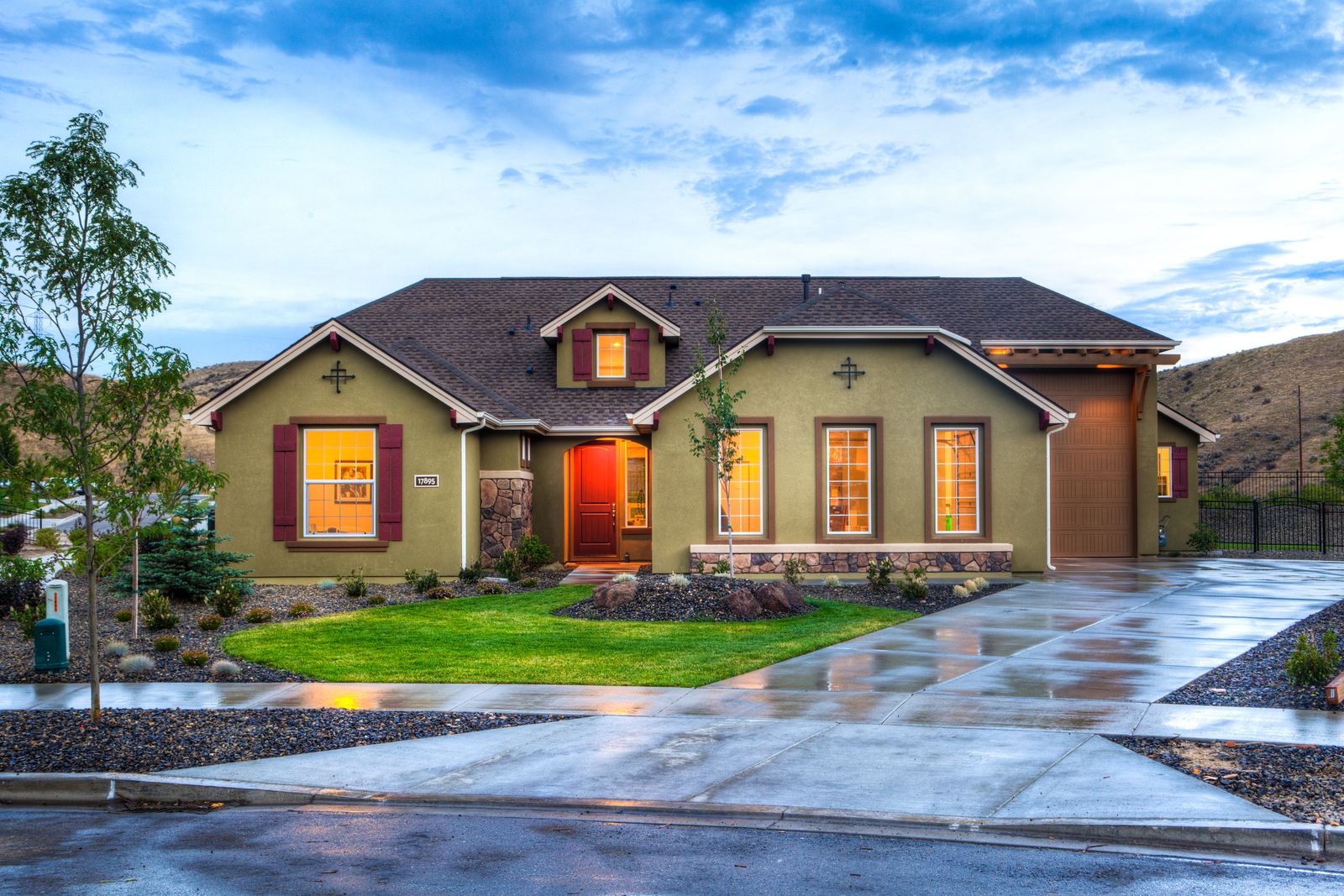 A custom-built Southern Utah home at dusk with iron fencing, stonework, and a clean concrete drive