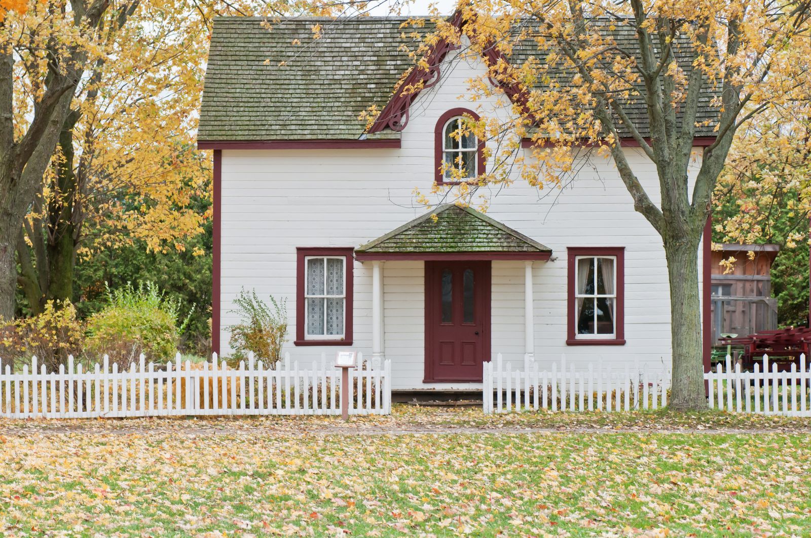 A clean white picket fence framing a tidy front yard and home