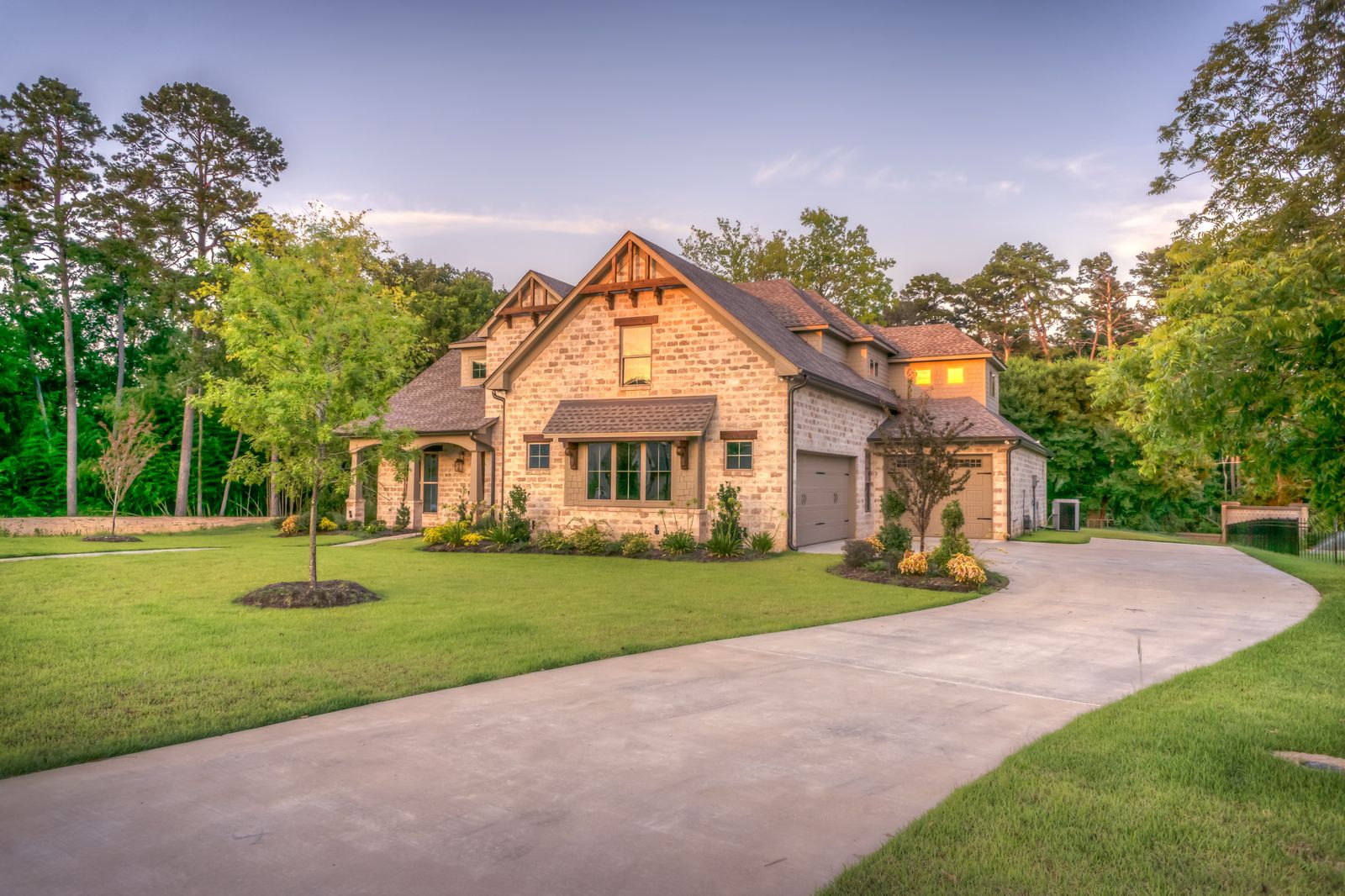 A large custom-built stone home with a sweeping driveway and iron fencing in Southern Utah