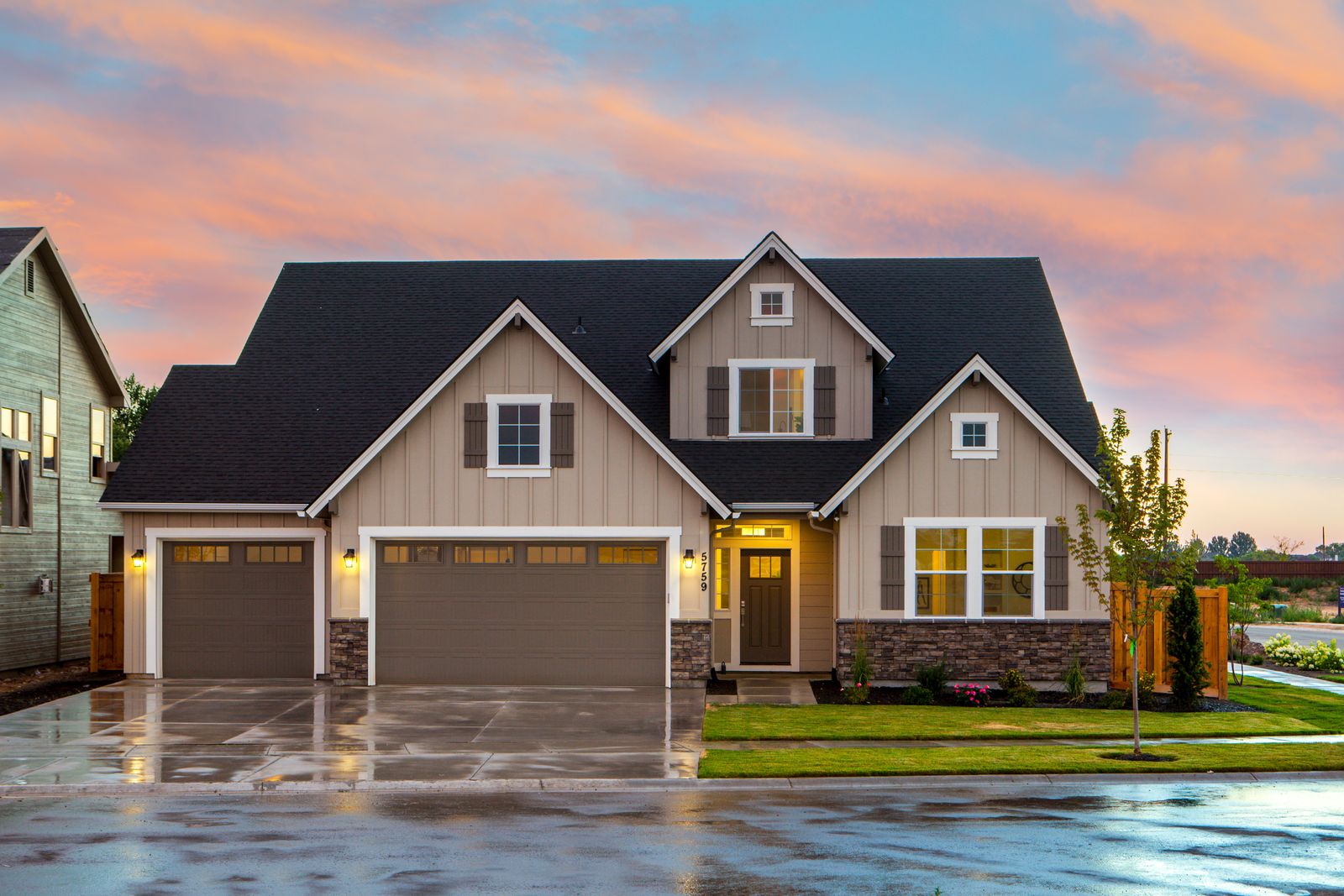 A newly built two-story home at sunset with a wood privacy fence along the side yard